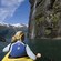 A woman in a kayak looks at waterfalls cascading down a cliffside